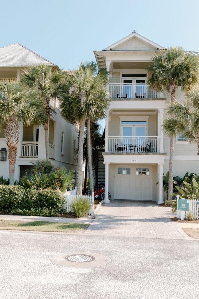 Charming three-story house with palm trees, ideal beachside living.