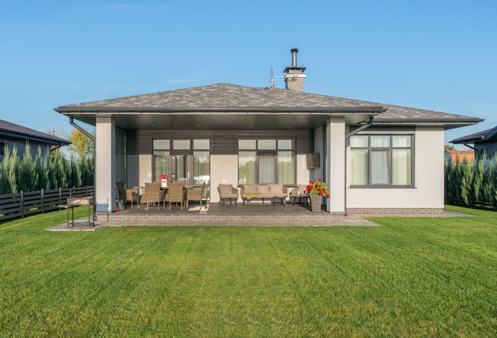 Contemporary house exterior with a large backyard patio and manicured lawn.